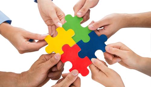Hands placing colourful puzzle pieces together